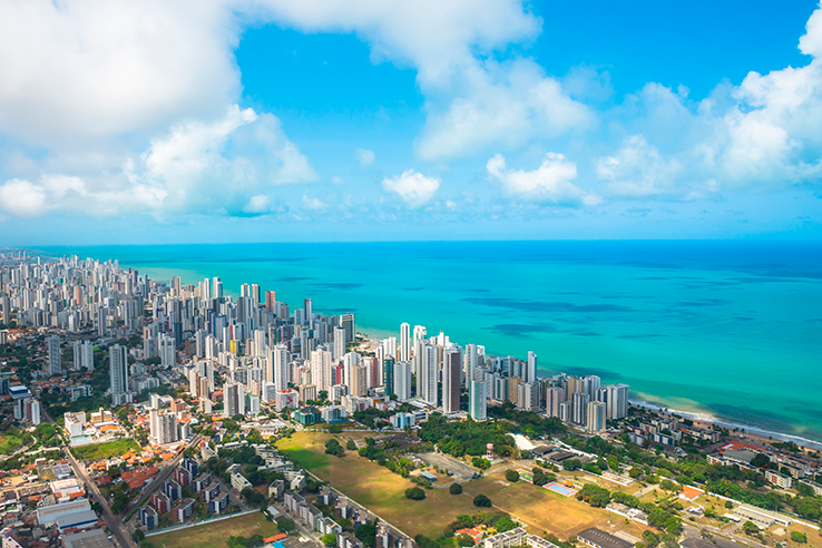 Imagem aérea da cidade de Recife com as casas e prédios e o mar logo atrás
