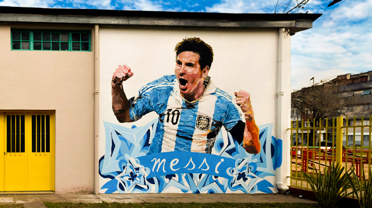 Parede com pintura do Messi comemorando e usando camiseta da Argentina.