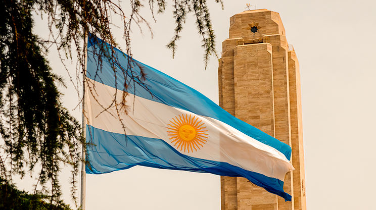 Bandeira argentina à frente de monumento.