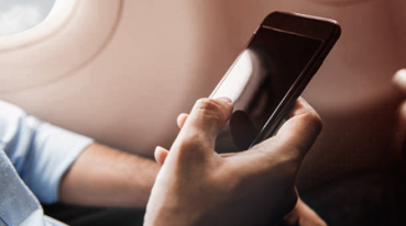 Pasajero con teléfono celular en la mano dentro del avión