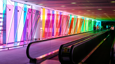 Esteira rolante do Aeroporto Internacional de Miami, iluminada pelos vitrais coloridos nas janelas da edificação.