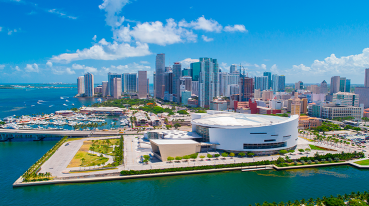 Vista panorâmica do centro de Miami, com arranha-céus imponentes e modernos dominando a paisagem urbana, com o oceano em volta da cidade.