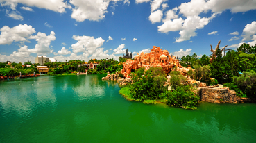 Vista panorâmica do Universal Orlando Resortt, com um grande lago de águas esverdeadas e vegetação ao redor.