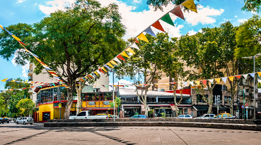 Praça em Palermo, com bandeirinhas coloridas instaladas e lojas ao fundo.