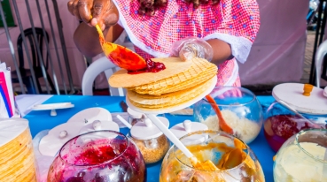 Mulher servindo oblea com recheios de arequipe e geleia de frutas vermelhas.