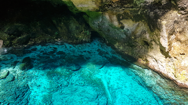 Caverna de Punta Cana vista de dentro, com lago azul entre as formações rochosas.