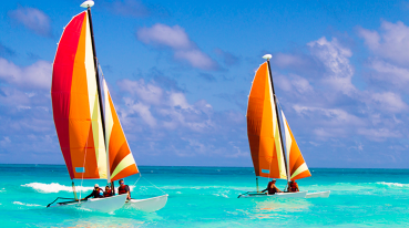 Mar de Punta Cana com dois veleiros catamarã com velas vermelhas.