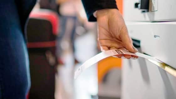 Imagem de uma pessoa retirando do totem a etiqueta de identificação para as malas